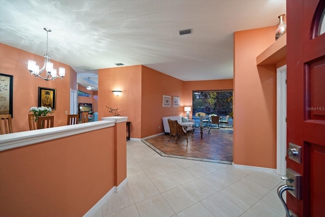 interior space with light tile patterned floors, visible vents, baseboards, and a notable chandelier