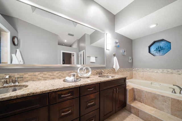 full bathroom featuring double vanity, backsplash, a garden tub, and a sink