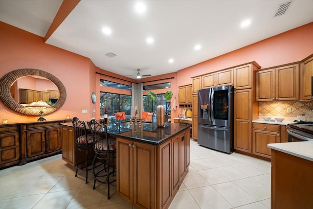 kitchen featuring visible vents, refrigerator with ice dispenser, a kitchen island, tasteful backsplash, and stainless steel electric range