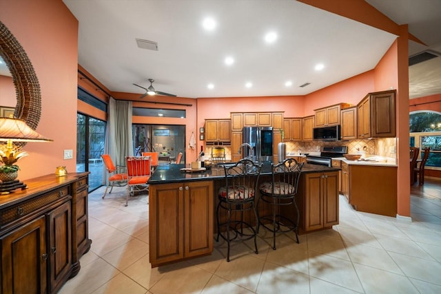 kitchen featuring a breakfast bar area, visible vents, appliances with stainless steel finishes, and brown cabinets