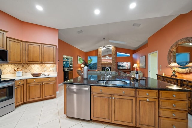 kitchen with lofted ceiling, ceiling fan, a sink, appliances with stainless steel finishes, and brown cabinets