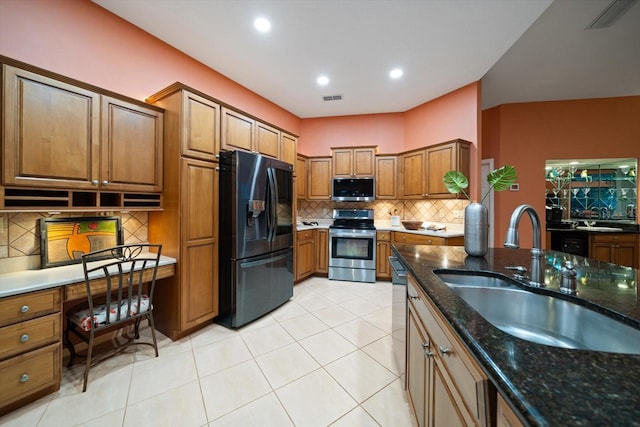 kitchen featuring visible vents, backsplash, brown cabinetry, stainless steel appliances, and a sink