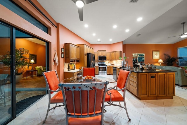 kitchen featuring a ceiling fan, a sink, backsplash, stainless steel appliances, and brown cabinetry