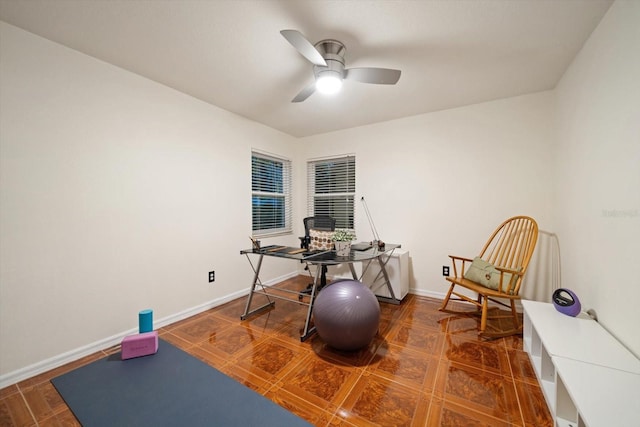 workout area featuring a ceiling fan and baseboards