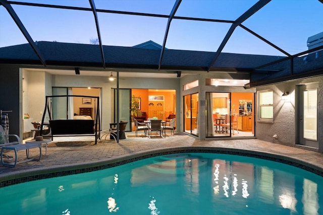 outdoor pool featuring glass enclosure and a patio