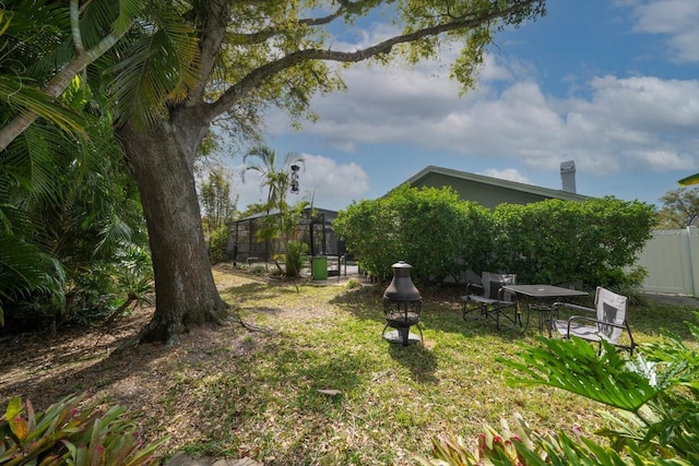 view of yard featuring glass enclosure, an outdoor fire pit, and fence