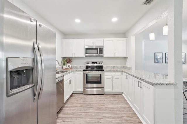 kitchen with a sink, stainless steel appliances, light stone countertops, and white cabinetry