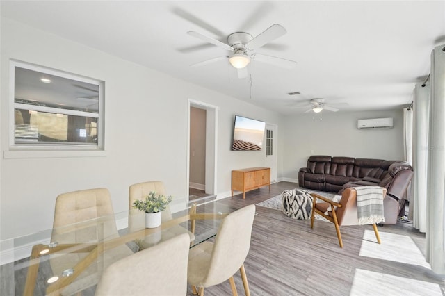 dining space with wood finished floors, a ceiling fan, baseboards, and a wall mounted AC