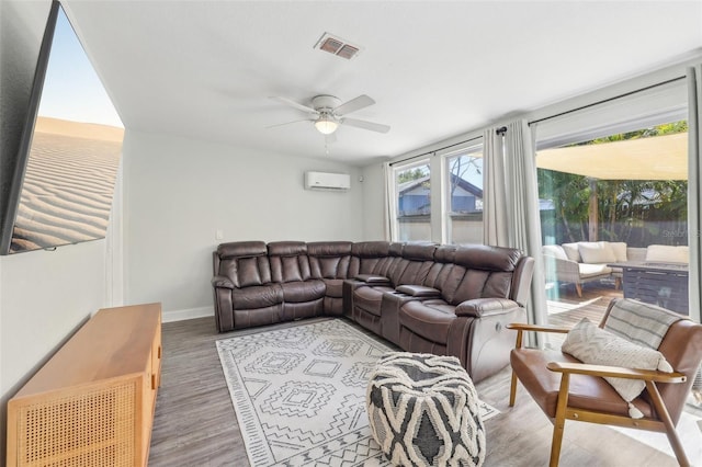 living room featuring a ceiling fan, baseboards, visible vents, an AC wall unit, and light wood-type flooring