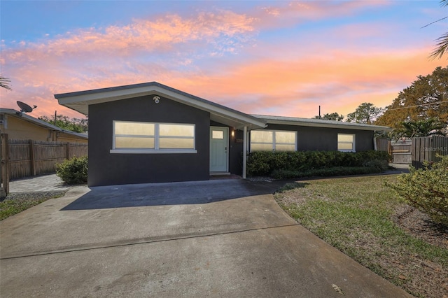 ranch-style home featuring stucco siding, a front yard, and fence