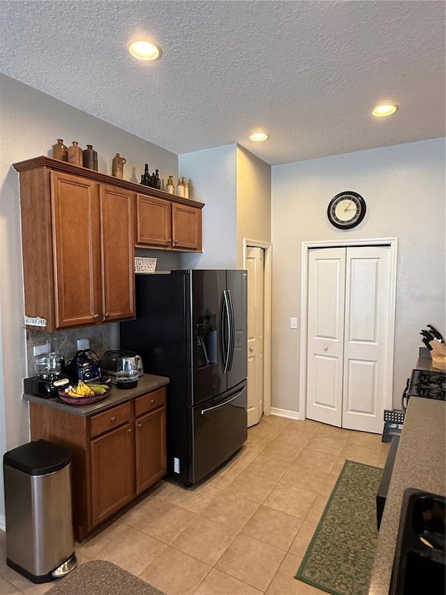 kitchen with dark countertops, recessed lighting, brown cabinets, and black refrigerator with ice dispenser