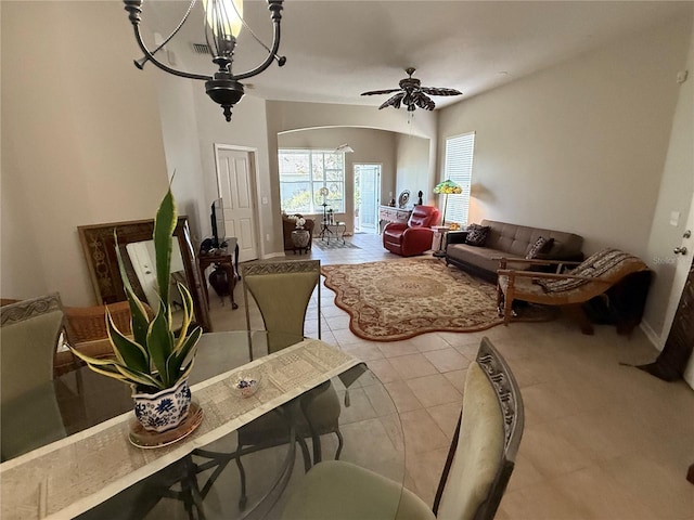 living area with arched walkways, visible vents, ceiling fan with notable chandelier, and light tile patterned floors