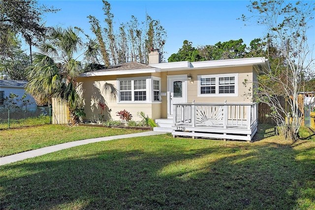 view of front of house with a front yard, stucco siding, fence, and a chimney