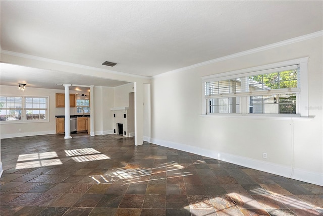 unfurnished living room featuring visible vents, baseboards, decorative columns, ornamental molding, and stone tile flooring