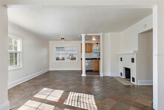 unfurnished living room featuring stone tile floors, crown molding, baseboards, and a sink