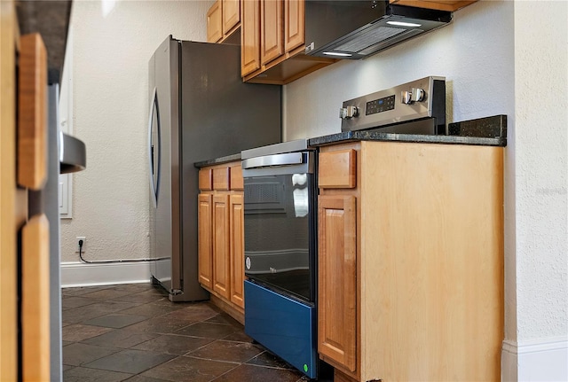 kitchen with dark countertops, baseboards, stainless steel electric stove, a textured wall, and stone tile flooring