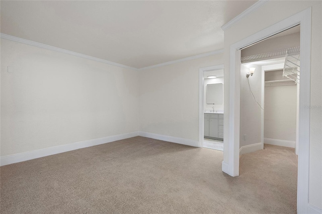 unfurnished bedroom with baseboards, carpet floors, a closet, crown molding, and connected bathroom