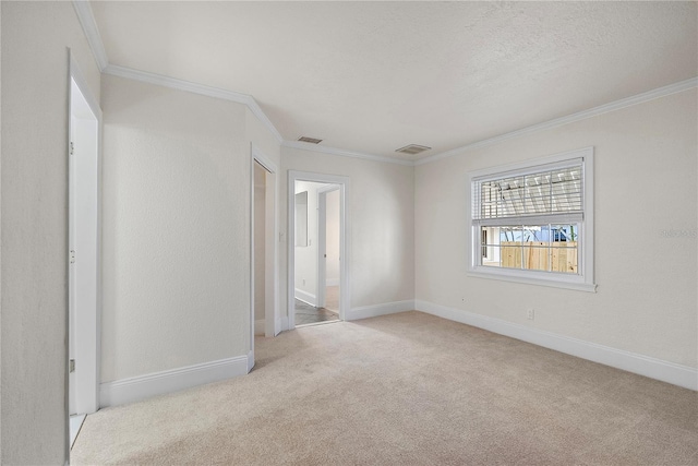 empty room featuring visible vents, baseboards, crown molding, and carpet