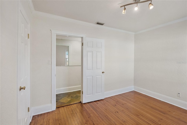 unfurnished room with visible vents, ornamental molding, baseboards, and hardwood / wood-style flooring