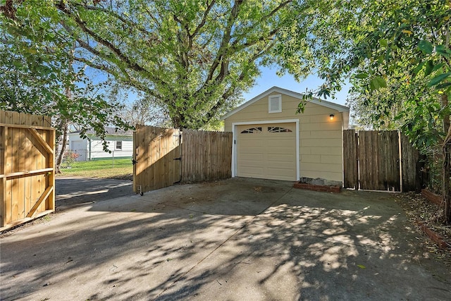 detached garage with concrete driveway and fence