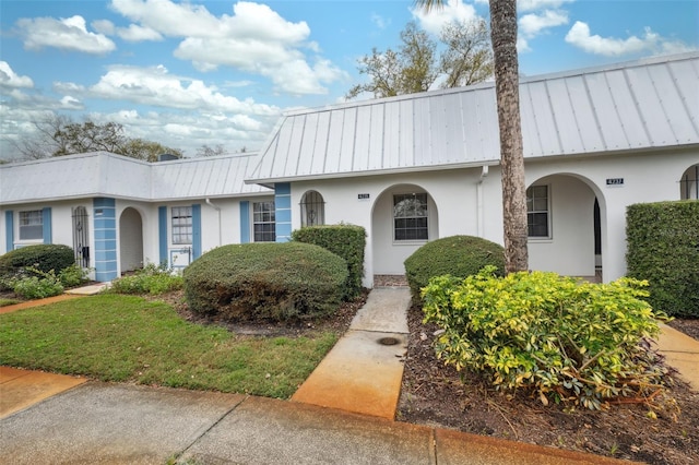 multi unit property featuring a standing seam roof, metal roof, and stucco siding