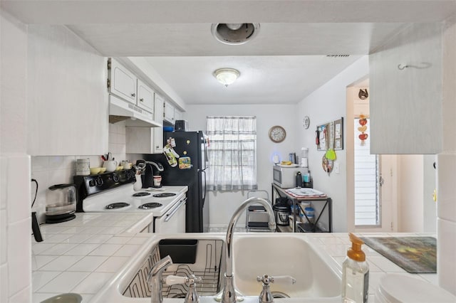 kitchen featuring tile counters, under cabinet range hood, decorative backsplash, white electric stove, and a sink