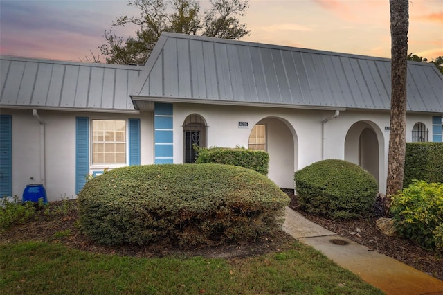 view of front of property with a standing seam roof, stucco siding, and metal roof