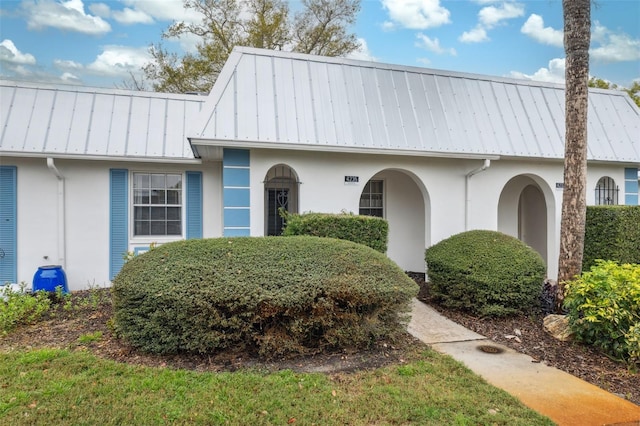 view of front of house with a standing seam roof, metal roof, and stucco siding