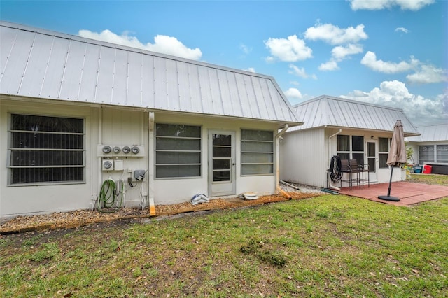 back of house with a yard, metal roof, and a patio area