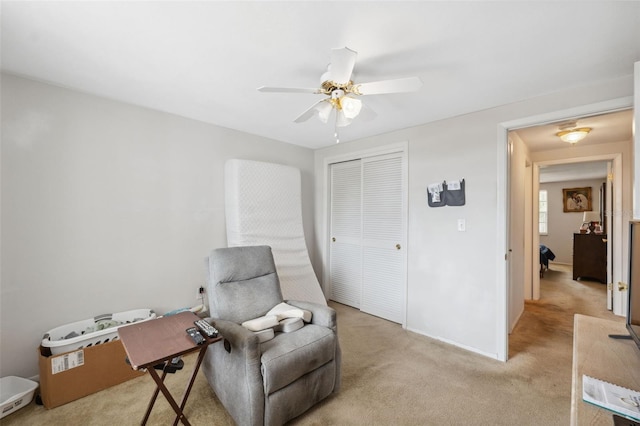 sitting room with a ceiling fan, light colored carpet, and baseboards