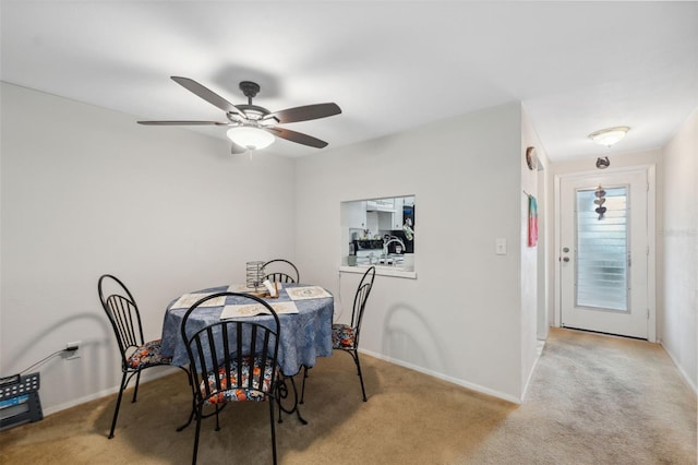 dining room with light carpet, baseboards, and a ceiling fan