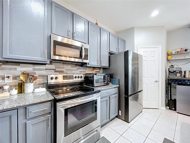 kitchen featuring a toaster, gray cabinets, and stainless steel appliances