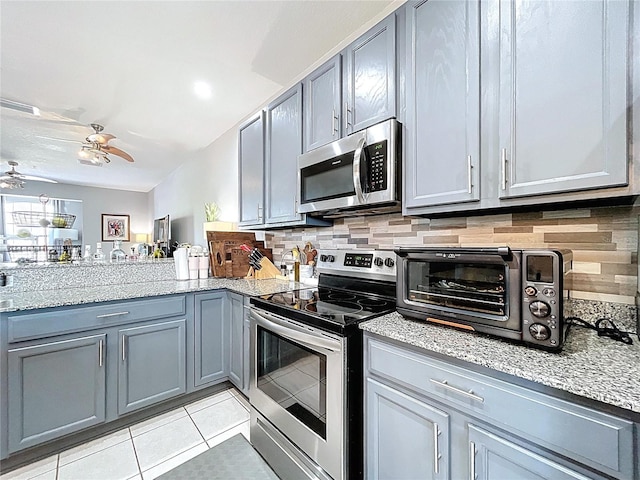 kitchen featuring light tile patterned floors, stainless steel appliances, backsplash, and gray cabinetry