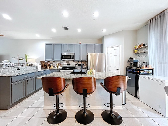 kitchen with visible vents, light tile patterned floors, gray cabinets, appliances with stainless steel finishes, and a sink