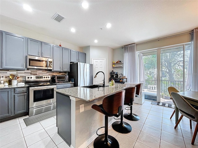 kitchen with light tile patterned floors, visible vents, gray cabinets, a sink, and appliances with stainless steel finishes