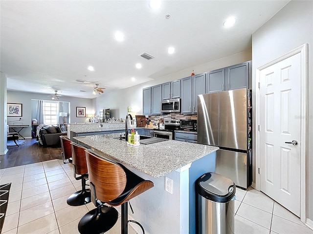 kitchen featuring a breakfast bar, light tile patterned flooring, stainless steel appliances, and a sink