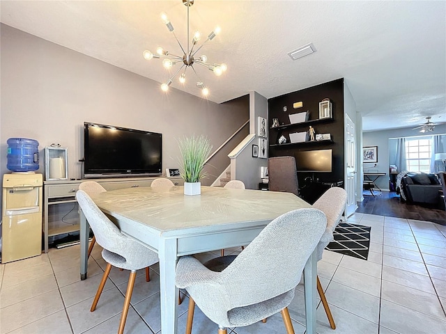 dining area with visible vents, a textured ceiling, an inviting chandelier, light tile patterned floors, and stairs