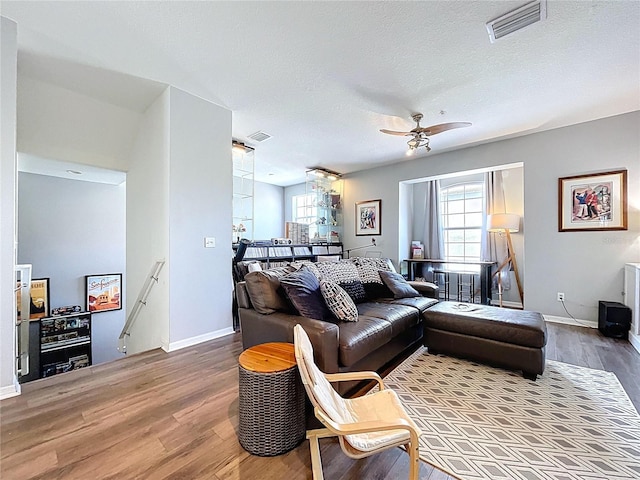 living area with visible vents, ceiling fan, and wood finished floors