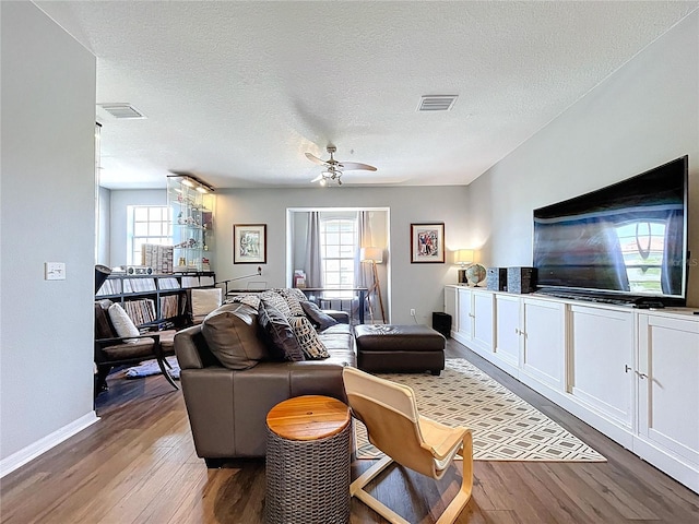 living room with baseboards, wood finished floors, visible vents, and a textured ceiling