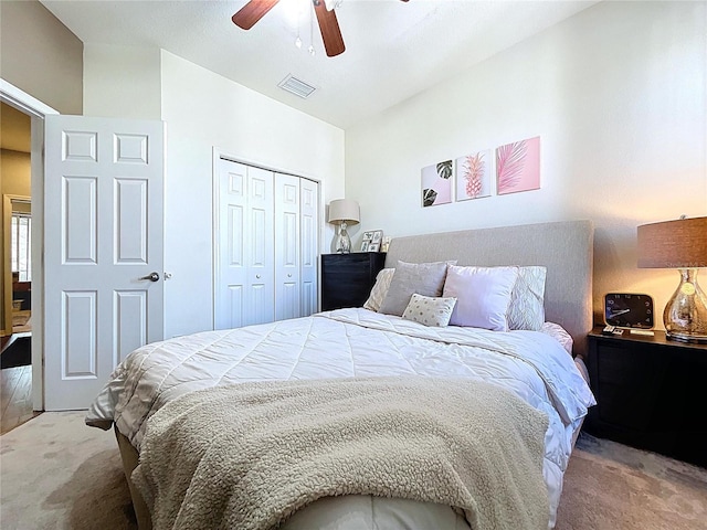 bedroom with visible vents, light colored carpet, a closet, and ceiling fan