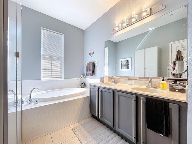 bathroom featuring tile patterned floors, double vanity, a bath, and a sink