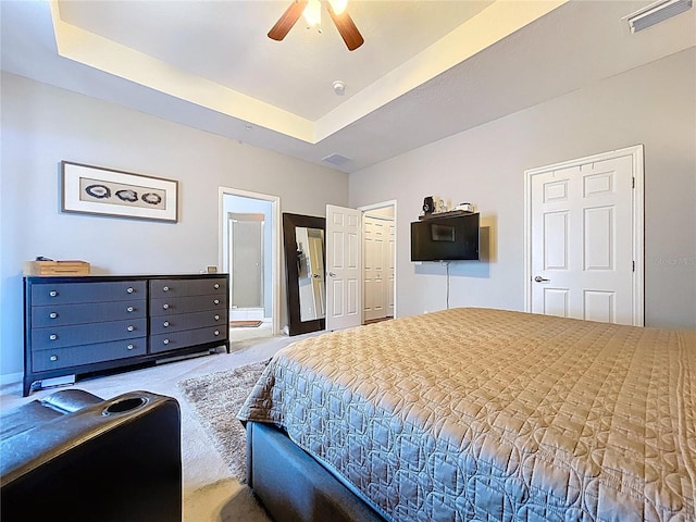 bedroom featuring visible vents, a ceiling fan, ensuite bathroom, carpet flooring, and a raised ceiling