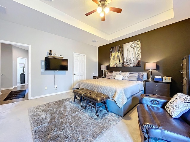 bedroom featuring visible vents, baseboards, a tray ceiling, ceiling fan, and carpet flooring