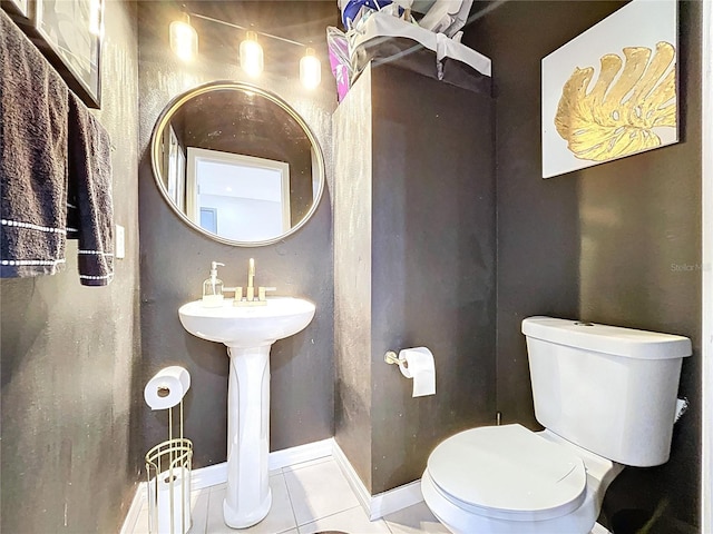 half bathroom featuring tile patterned flooring, toilet, and baseboards