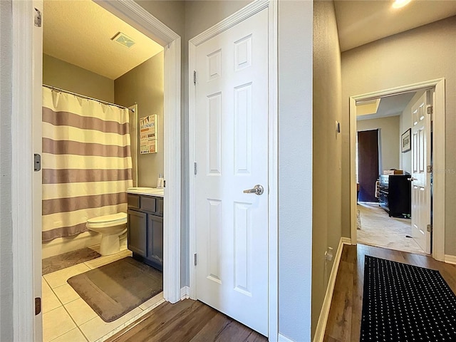 full bath featuring visible vents, toilet, wood finished floors, baseboards, and vanity