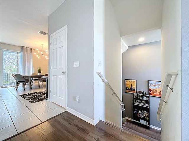 staircase with visible vents, baseboards, an inviting chandelier, and wood finished floors