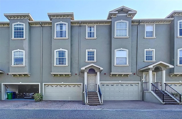 multi unit property with stucco siding, an attached garage, and driveway