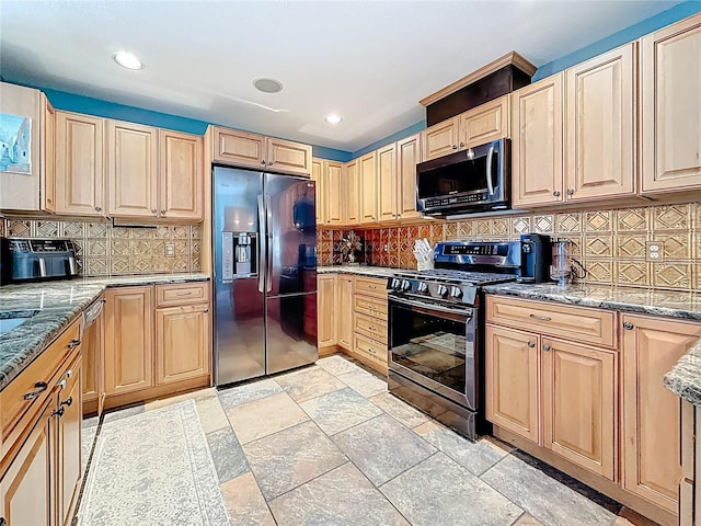 kitchen with stainless steel range with gas cooktop, light stone counters, refrigerator with ice dispenser, decorative backsplash, and stone tile flooring