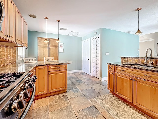 kitchen featuring visible vents, a sink, decorative light fixtures, a peninsula, and gas range