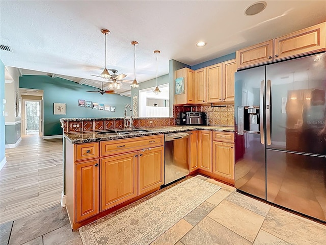 kitchen featuring a ceiling fan, a peninsula, a sink, stainless steel appliances, and backsplash